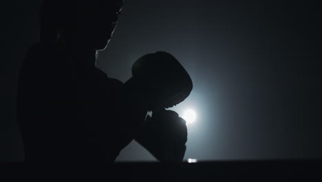 silhouette of a boxer training in a dark gym