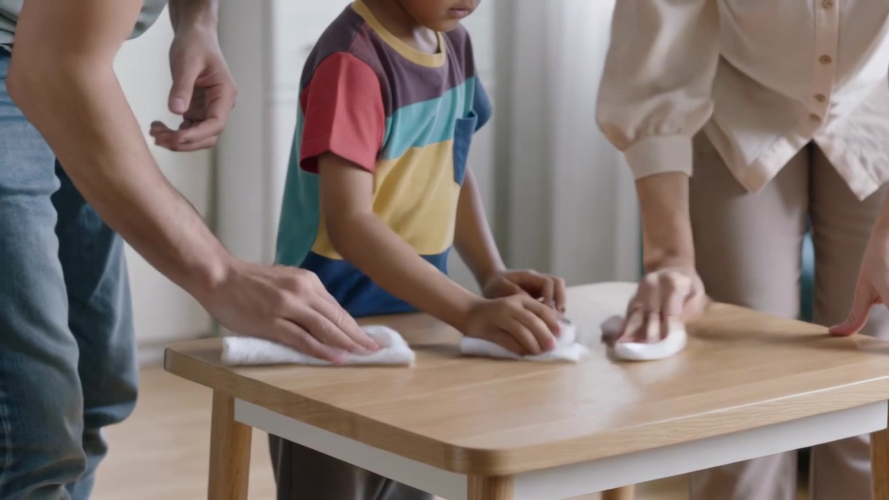 Starting parents wiping, family cleaning table with white cloths at home, child striped tee helping
