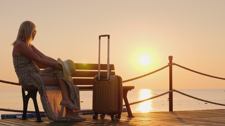 La jeune fille attend de s'installer à l'hôtel sur la jetée maritime, assise avec ses valises et profite...