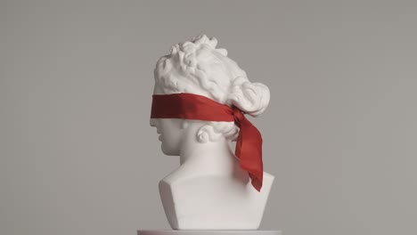 white statue bust with red blindfold