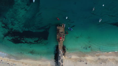 Toma-Aérea-De-Arriba-Hacia-Abajo-Del-Famoso-Muelle-De-Madera-Y-Playa-En-Santa-María,-Isla-De-Sal,-Cabo-Verde