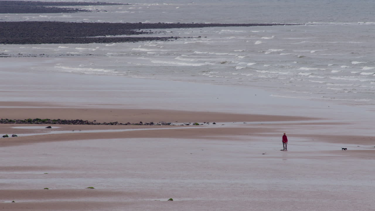long shot of Saint bees beach with dog Walker. West lake district