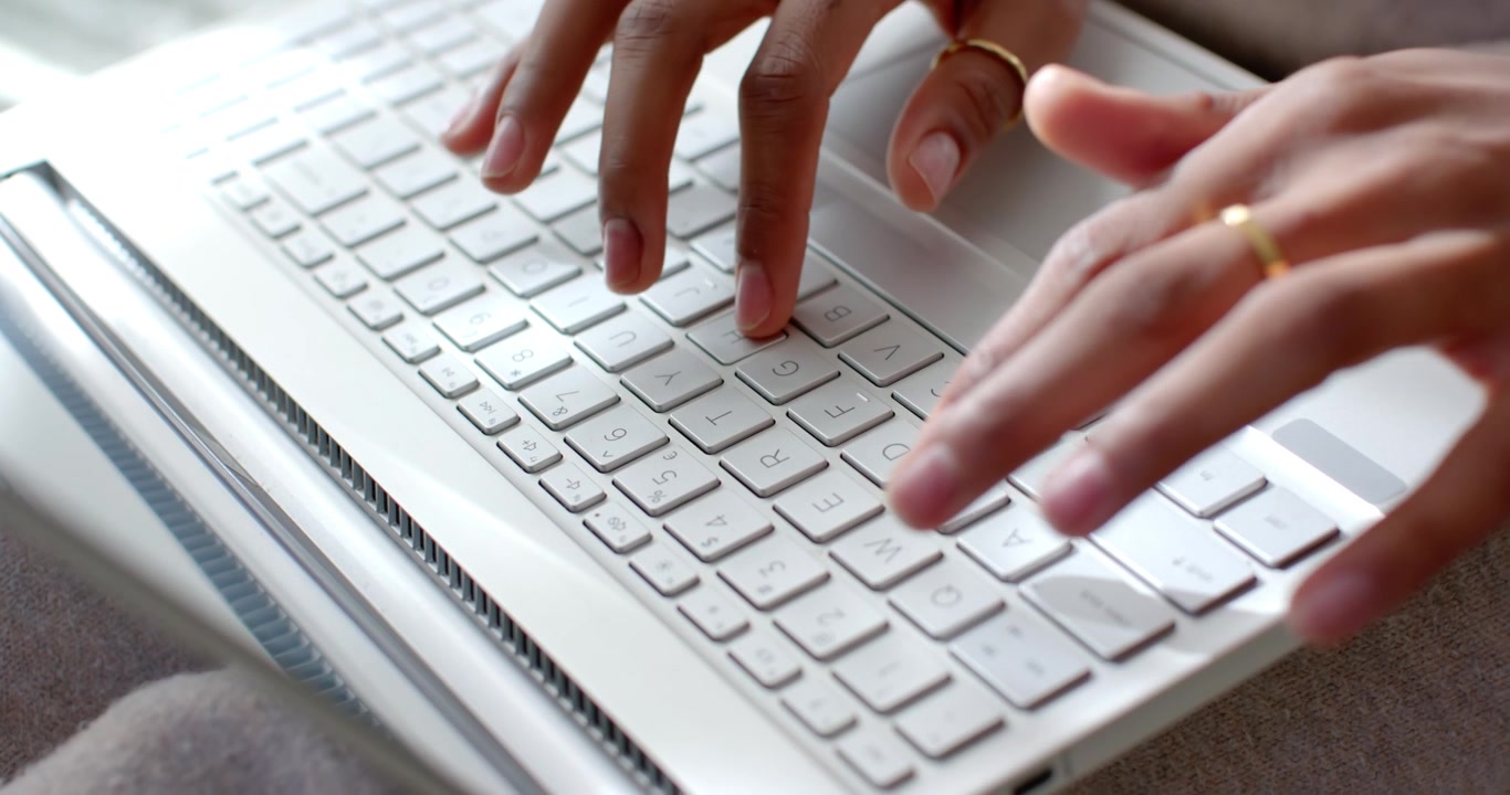 Mani che iniziano a digitare ritmicamente da una posizione di riposo su una coperta, battendo su una tastiera bianca per scrivere un testo.