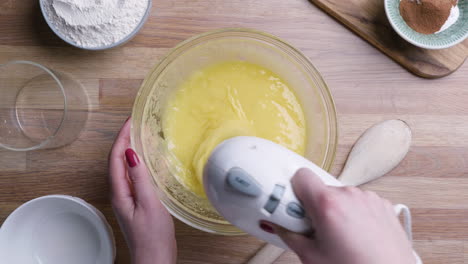 beaten eggs with mixer whisks in bowl for baking carrot cake - high angle shot