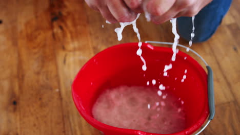 close up of man squeezing water into bucket after domestic leak