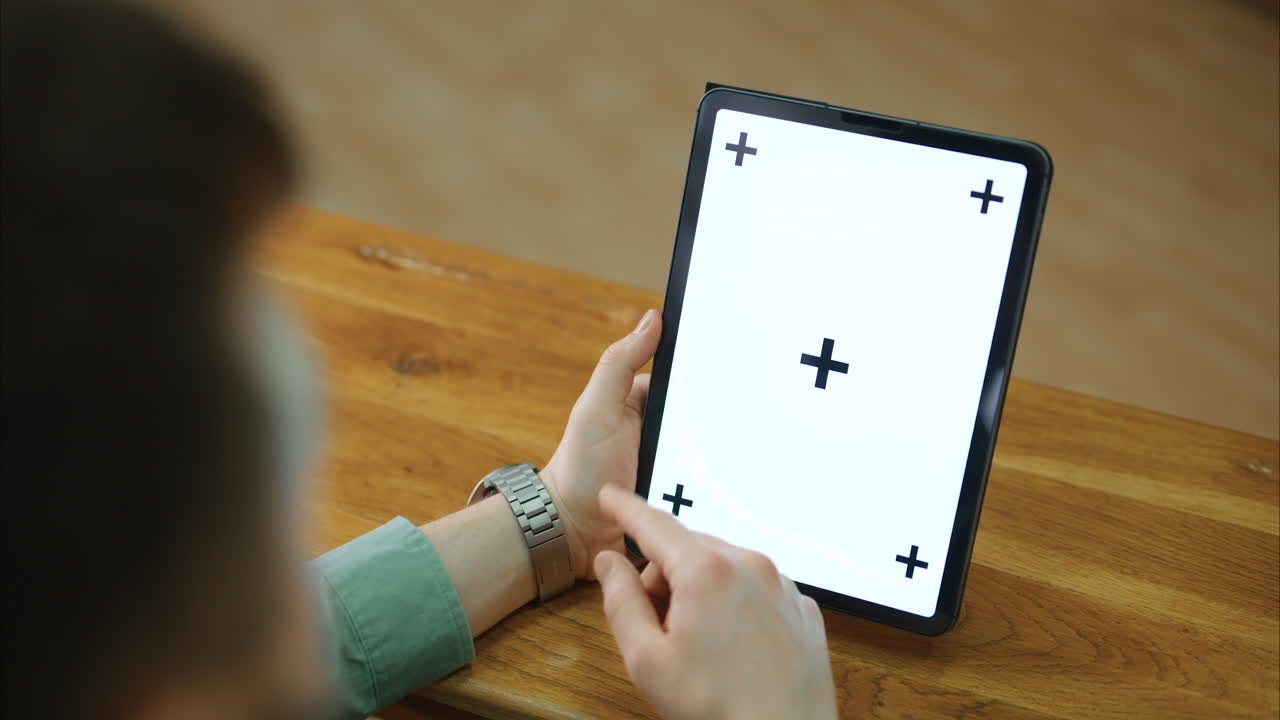 Hands of a man swiping on a tablet with white screen and tracking points, chroma key ready.