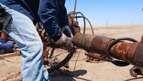 unrecognized man in dirty gloves disassembles the parts from the pipe. worker maintaining the equipment for drilling gas and oil.