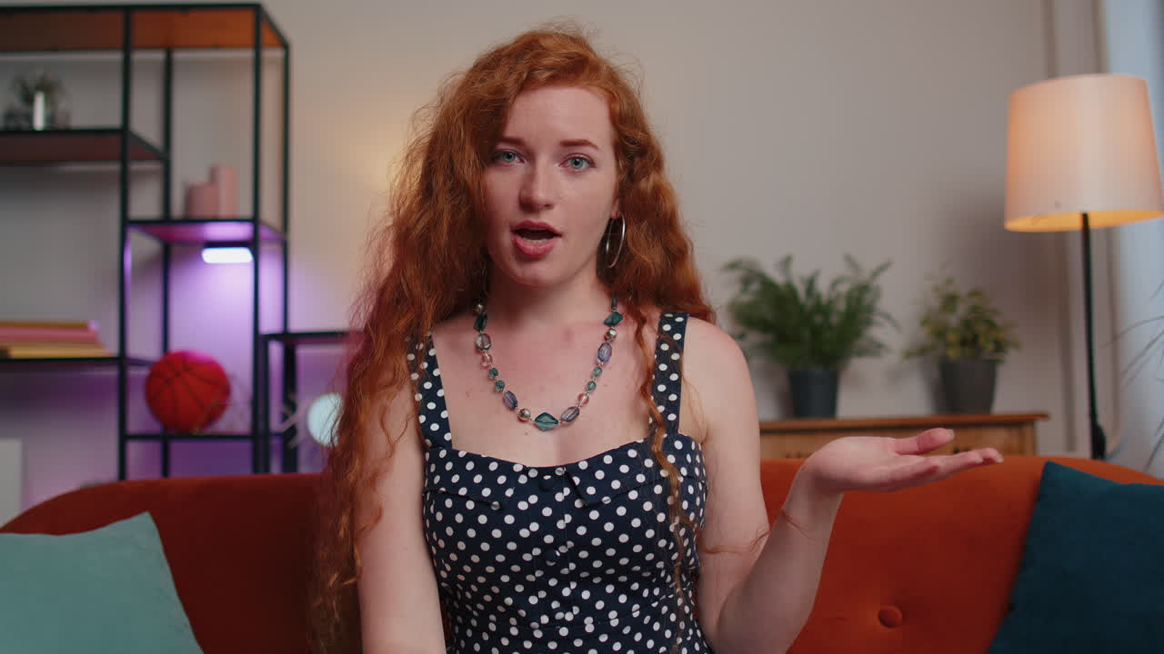 mujer sentada en el sofá de casa, mirando a la cámara, haciendo una llamada de videoconferencia con amigos o familiares