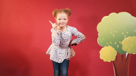 little cute little girl in the studio. cute redheaded child on red background