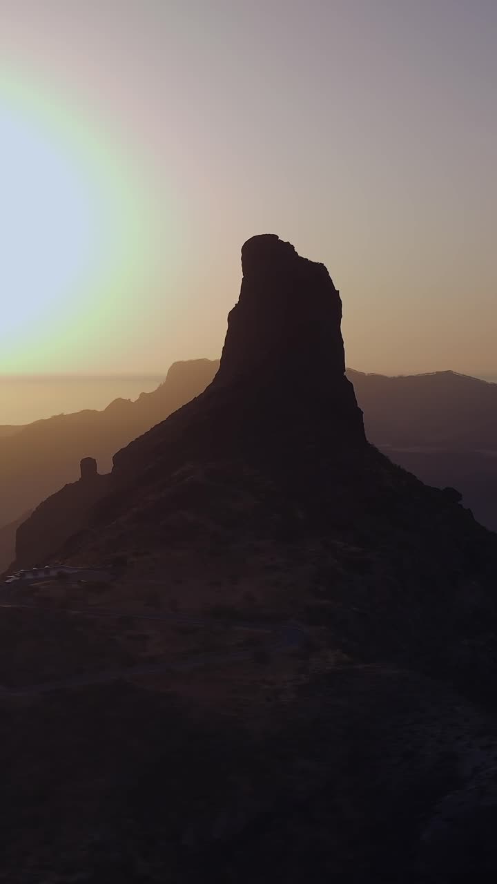 Magnifica vista aerea di Roque Bentayga stagliato contro un cielo dorato al tramonto. Il sole tramonta sotto l'orizzonte a Gran Canaria