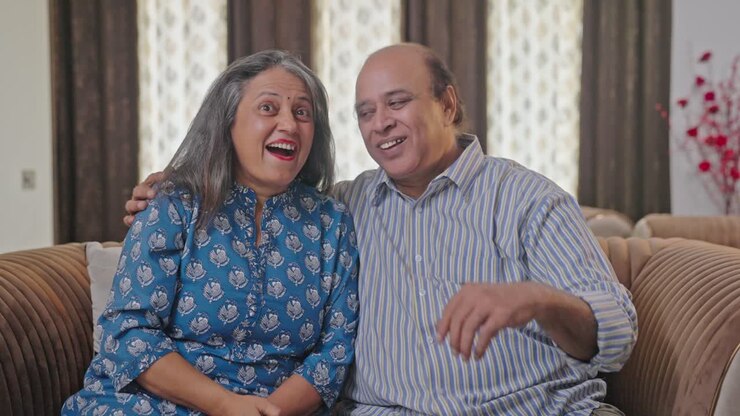 una vieja pareja india viendo televisión y sonriendo