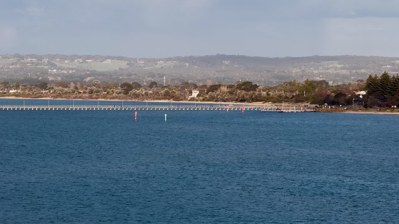 Camera smoothly pans across Rye pier, blue bay waters, and distant shoreline under natural daylight