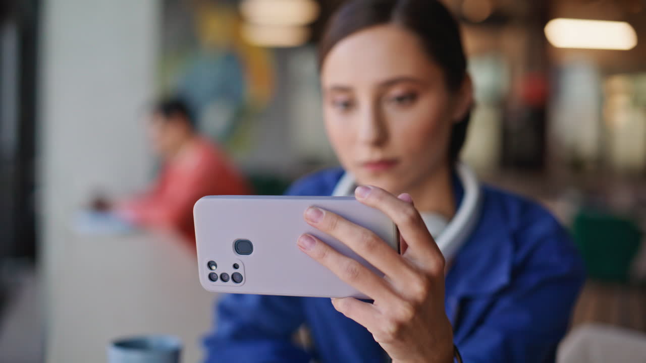 Joyful woman browsing cellphone social media app in cafe closeup. Smiling girl