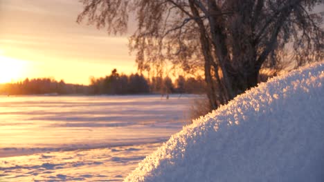 golden winter sunrise lighting up fresh snow at frozen lake on ice cold winter day, sliding close shot