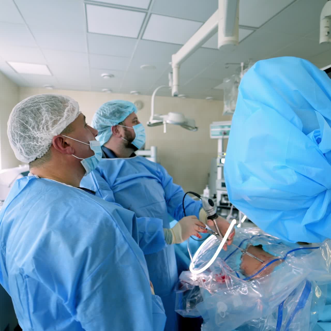 Group of doctors perform an operation to a patient. Surgeons in medical uniform and masks working in the operating room.