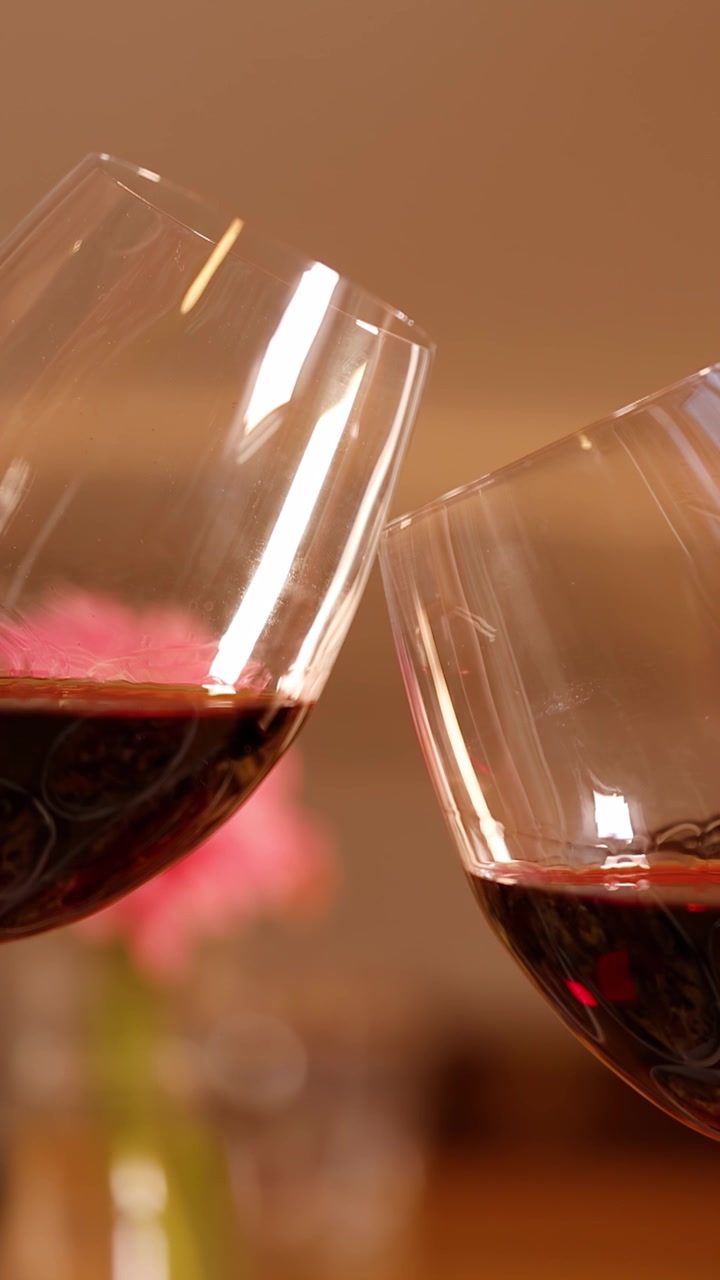 Due calici di vino rosso brindano durante un appuntamento a cena con un'illuminazione interna calda