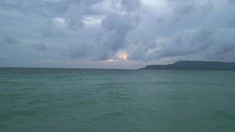 camera moves over a windy beach out towards a vast ocean beneath a cloudy sky.