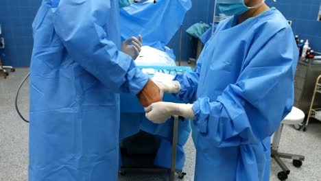 nurse helping a surgeon in wearing surgical gloves