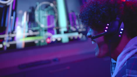 a young biracial man is talking on his gaming headset with copy space at home, playing video games