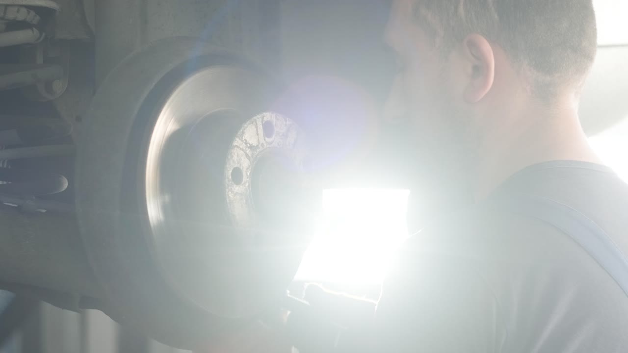 mecánico de automóviles inspeccionando el disco de freno del automóvil