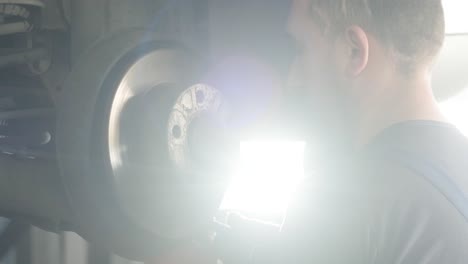 mecánico de automóviles inspeccionando el disco de freno del automóvil