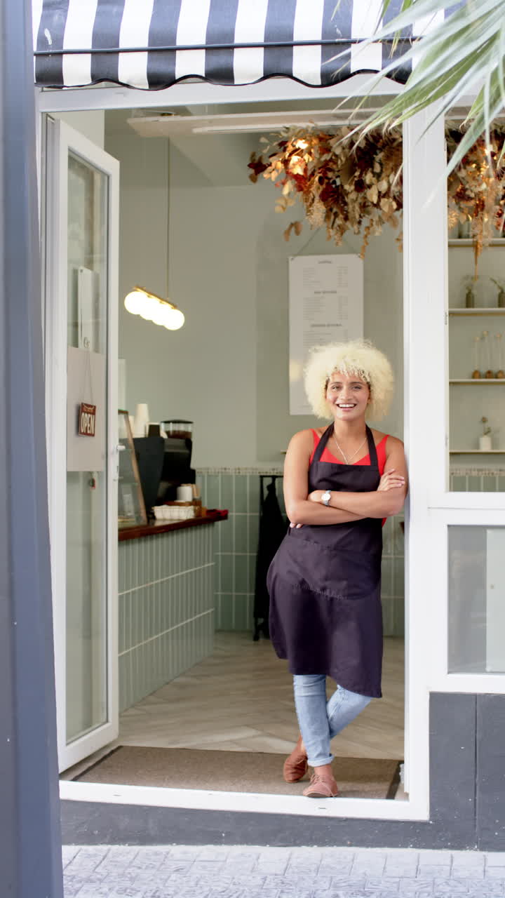 Vertical video: Female barista standing at cafe entrance, smiling and welcoming customers