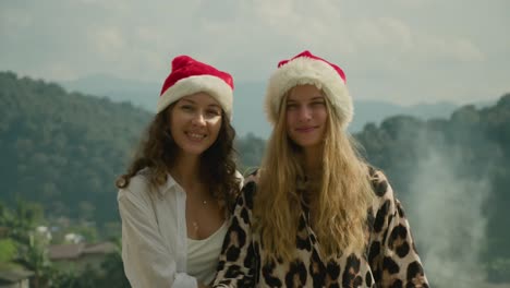 two women wearing christmas hats in the mountains