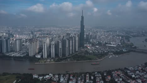 Escena-Aérea-De-Hiperlapso-De-La-Ciudad-De-Ho-Chi-Minh-Del-Edificio-Emblemático,-El-Río-Saigón,-El-Cielo-Espectacular-Durante-El-Día-Y-El-Tráfico-De-Barcos-En-El-Agua