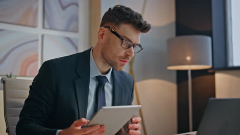 serious specialist watching tablet comparing computer screen at office closeup