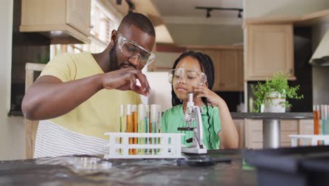 Focused-african-american-father-and-daughter-doing-science-experiments-at-home