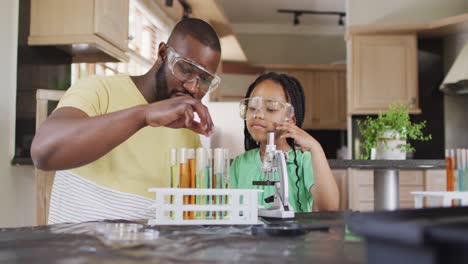 padre e hija afroamericanos enfocados haciendo experimentos científicos en casa