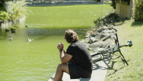 Side-view-of-man-with-disability-watching-ducks-in-river