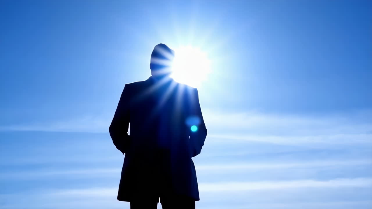 Silhouette of a person standing against a bright blue sky with a sun halo