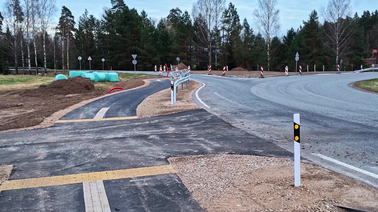 Budowa drogi z nowym skrzyżowaniem, ścieżką rowerową i barierami ochronnymi.