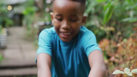 retrato de un feliz niño afroamericano plantando en el jardín