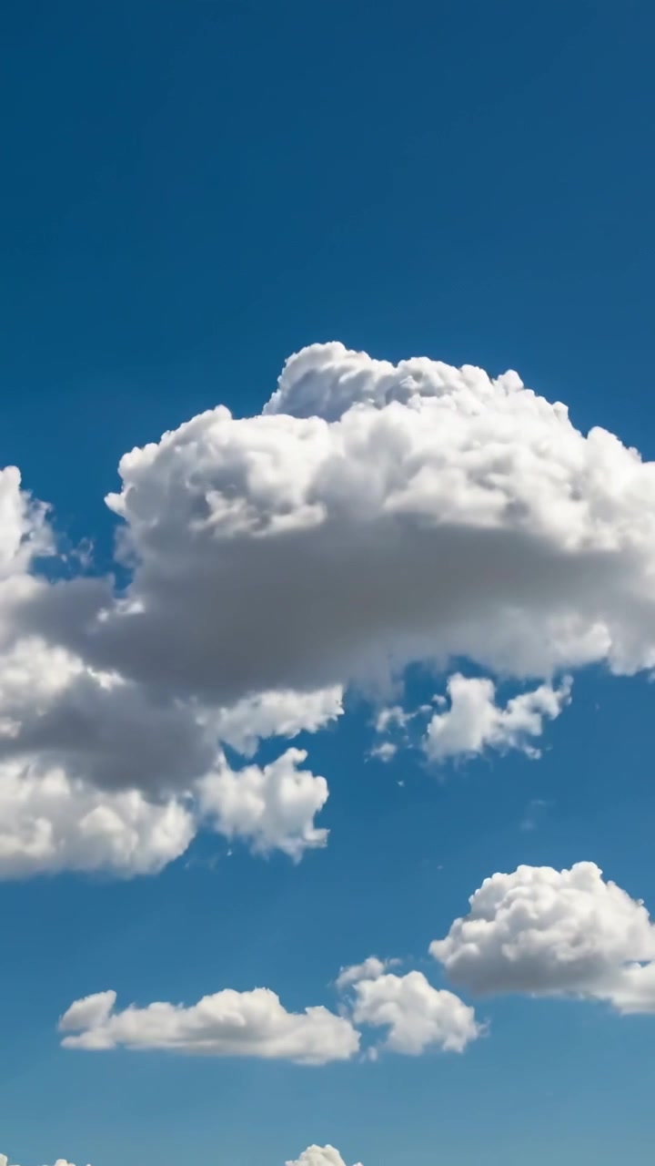 Video vertikal: Awan kumulus besar bergeser melayang ke kanan di langit biru, angin sepoi-sepoi mendorong awan-awan kecil.