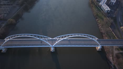 cars commuting over the arkansas river bridge at sunrise in little rock, aerial tracking shot.