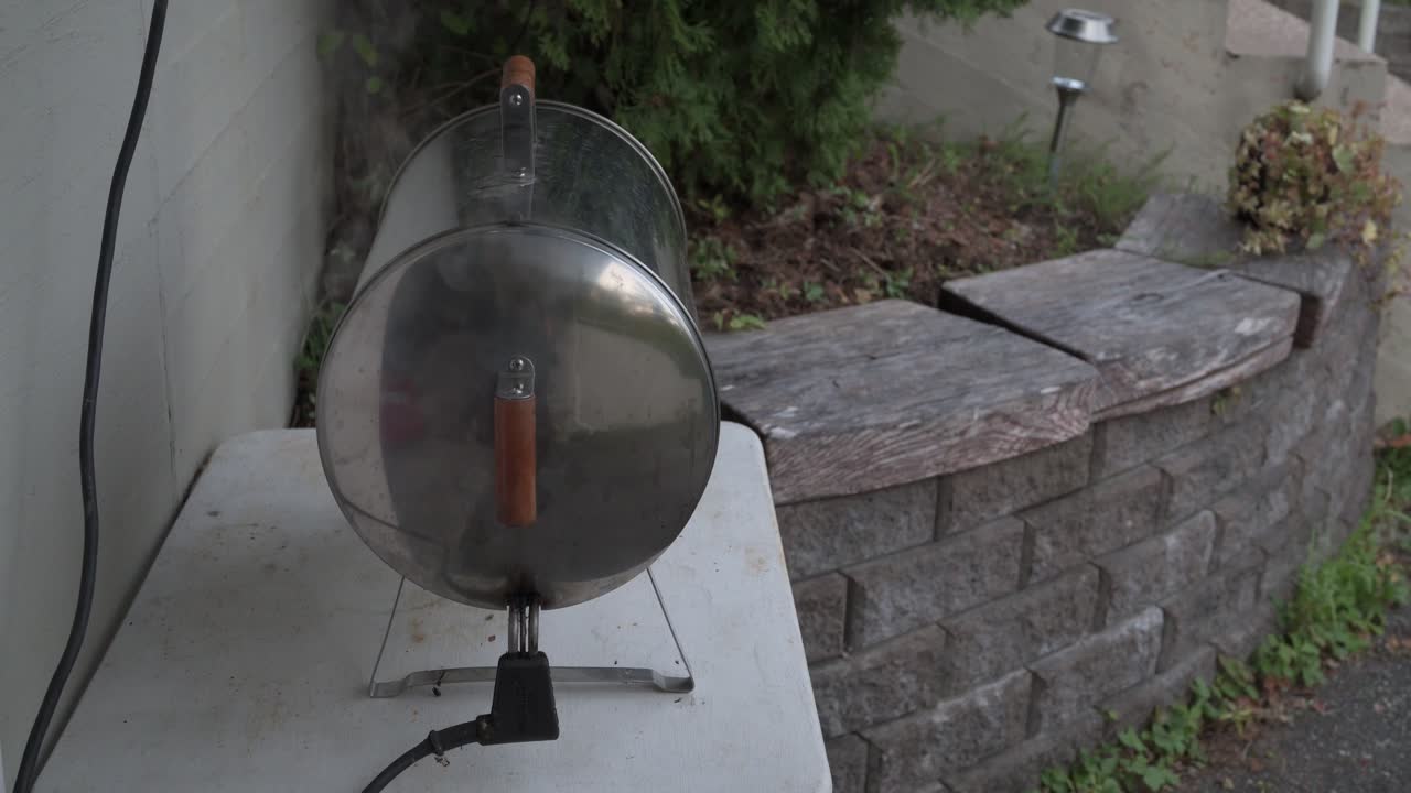 Electric smoker cooker outdoors with smoke coming out from machinery