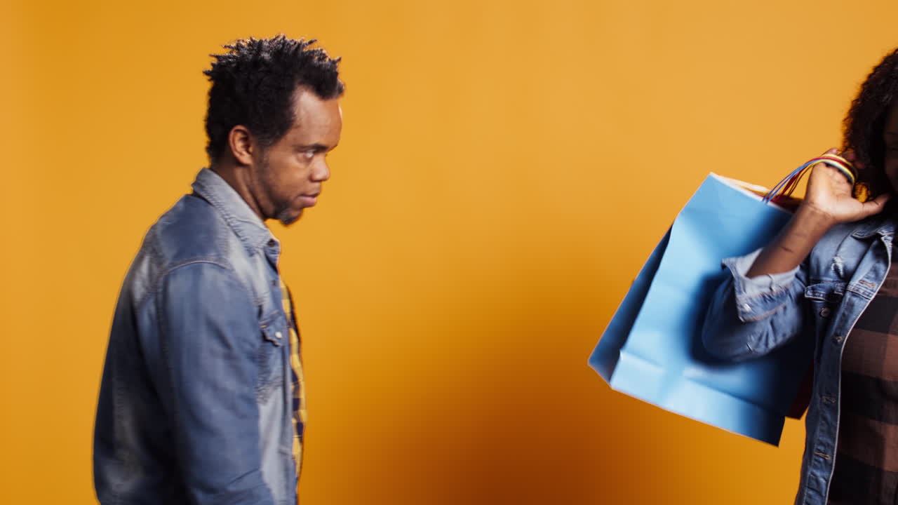 쇼핑 가방 을 들고 있는 아프리카계 미국인 여자 가 남편 과 함께 따라가고 있다