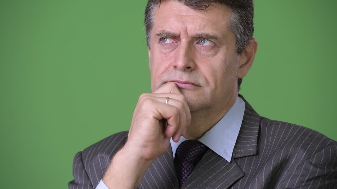 hombre de negocios maduro y guapo contra un fondo verde