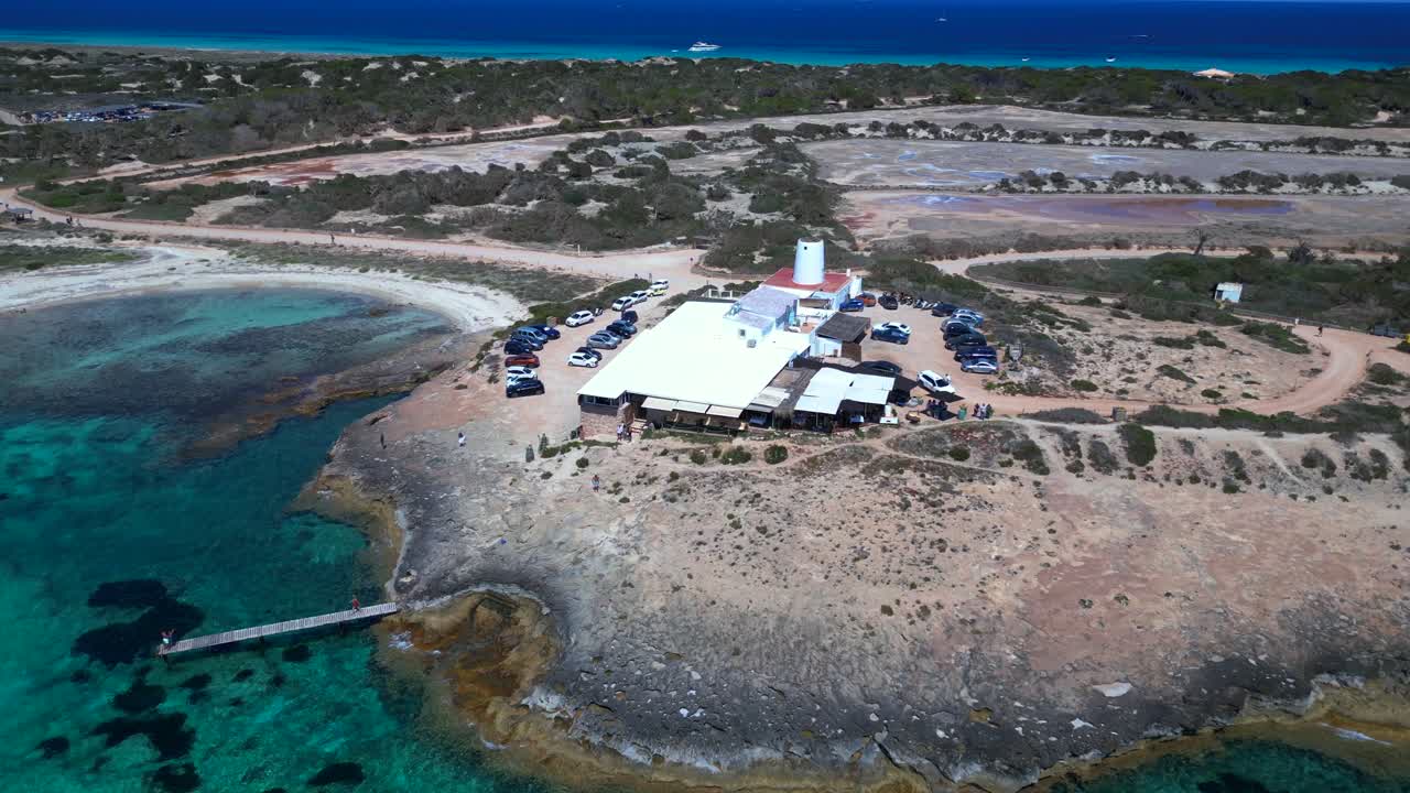 Sailboats anchored in turquoise waters near a beach Restaurant on the idyllic island Formentera, Spain. Magic aerial view flight drone shot footage from above