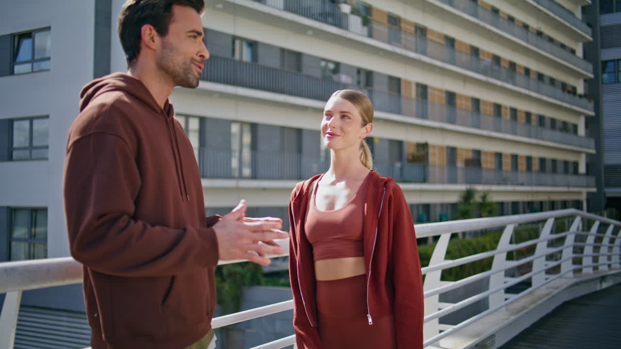 Personal trainer talking girl on sunny street. Smiling fitness couple flirting