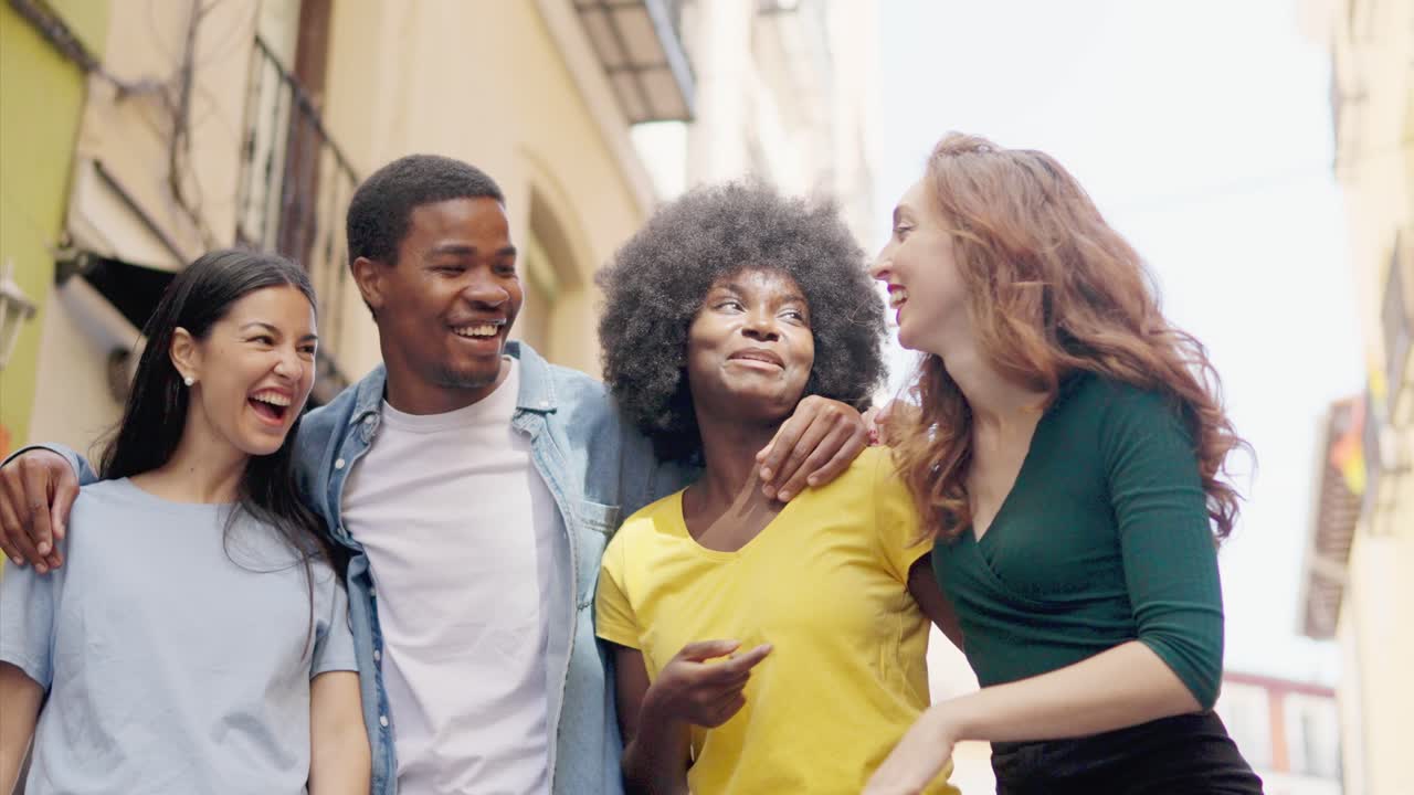 Diverse group of happy friends laughing and walking on a city street
