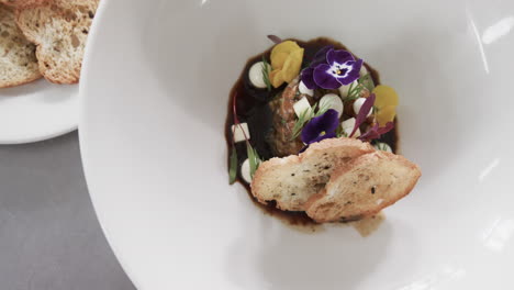 prepared and decorated meal on white plate in kitchen, slow motion