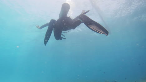 scuba diver ascending to surface with sun illuminating ocean