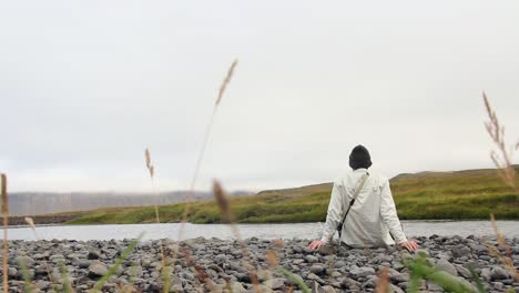 El-Hombre-Se-Relaja-Sentado-Al-Lado-De-Un-Río,-Clima-Sombrío