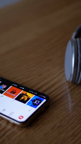 smartphone with headphones on wooden table