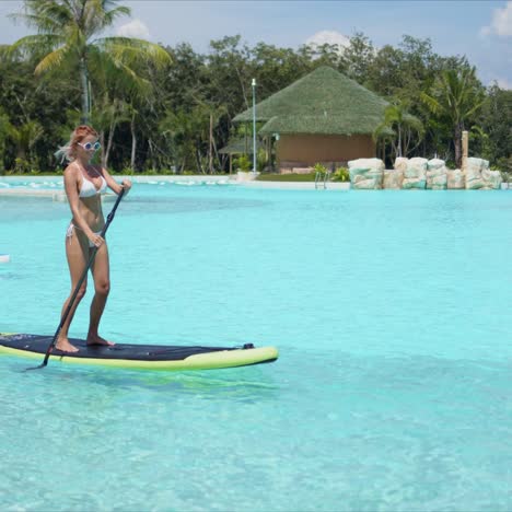 woman floating on paddle board in large swimming pool