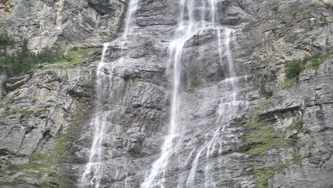 giant waterfall over the rocks falling down on a bright day in lauterbrunnen in switzerland. slowmotion medium shot.