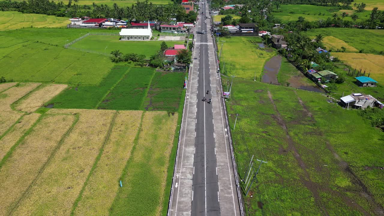 Aerial overview of lone highway surrounded by lush green fields at Malilipot, Albay, Philippines.